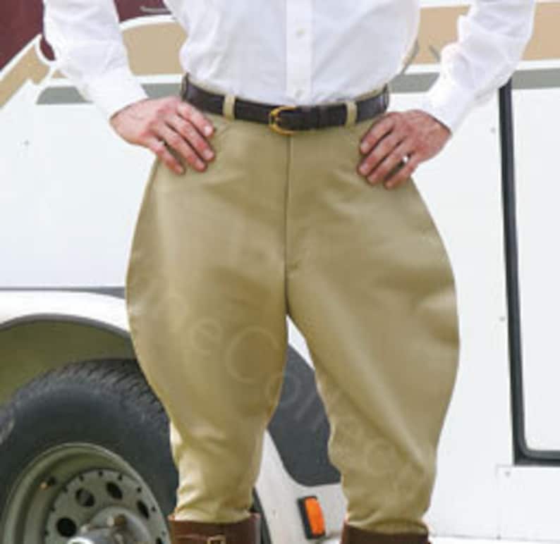May include: Beige riding breeches with a brown leather belt. The breeches have a slightly flared leg and are made of a smooth, lightweight fabric.