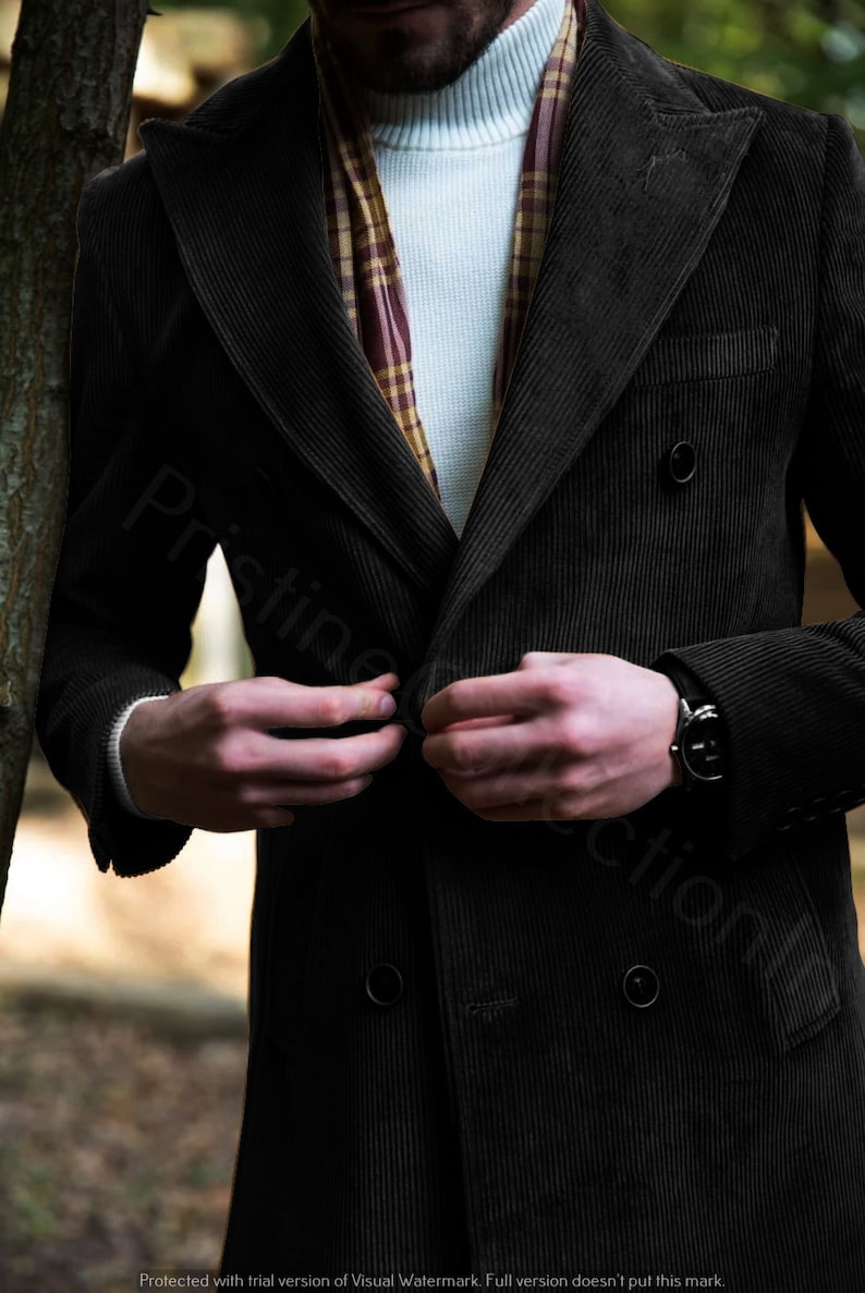 May include: A black corduroy double-breasted jacket with a button closure. The jacket has a pocket on the left side and a brown and white plaid scarf is worn underneath.