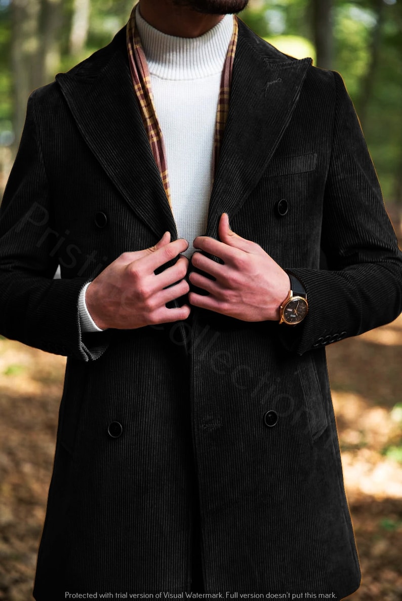 May include: A black corduroy double-breasted coat with a brown and yellow patterned scarf. The coat has two buttons on the front and a pocket on the left side.