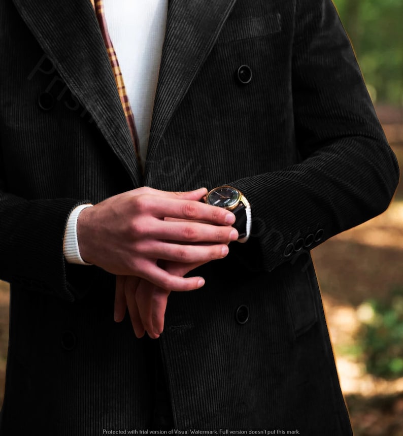 May include: A black corduroy double-breasted jacket with a gold watch on the left wrist.