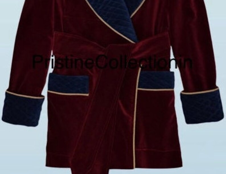 May include: A deep burgundy velvet robe featuring navy blue quilted lapels, cuffs, and pocket accents with gold piping trim. The garment includes a matching tie belt and the text PristineCollection in black lettering across the center front.