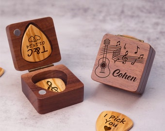 May include: Two wooden boxes with guitar pick holders. One box has a guitar and music notes engraved on it with the name "Cohen" and the other box has a pick with the text "T.C.  Love you" in Japanese.  There are three guitar picks on the table, one with the text "I Pick You" and a heart.