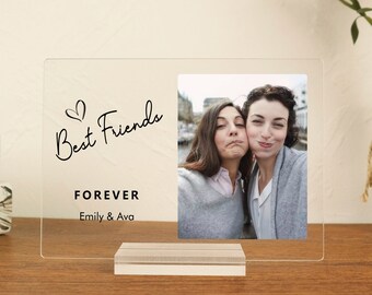 May include: A clear acrylic photo frame with a white stand. The frame has a photo of two women smiling and the text "Best Friends Forever Emily & Ava" printed on it.