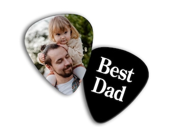 May include: Two guitar picks, one white with a photo of a father and daughter, and one black with the text "Best Dad" in white.