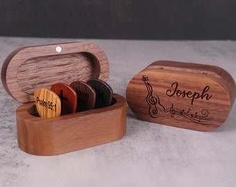 May include: A wooden box with a guitar and music notes design engraved on the lid. The box is personalized with the name "Joseph". The box is open and shows a set of guitar picks inside.
