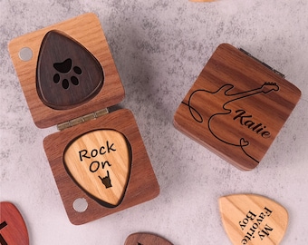 May include: A set of six wooden guitar picks with various designs and engravings. The picks are in a wooden box with a hinged lid. The designs include a paw print, a guitar, the words "Rock On", the words "My Favorite Boy", the initials "D&M", and the word "You".