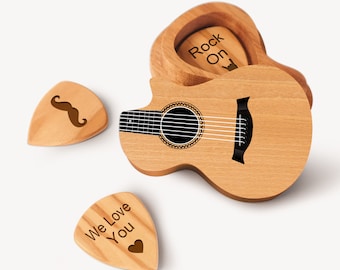May include: A wooden acoustic guitar with a pickguard and a soundhole. The guitar is in a wooden case with a pick inside. The pick has the words "Rock On" engraved on it. There are two other picks with the words "We Love You" and a mustache engraved on them.