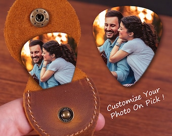May include: A brown leather guitar pick holder with a snap closure. The holder has a guitar pick inside with a photo of a couple. The text "Customize Your Photo On Pick!" is written on a wooden surface.