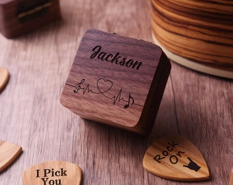 May include: A wooden box with the name "Jackson" engraved on the top. The box has a heart beat design with musical notes. The box is surrounded by guitar picks with various sayings, including "I Pick You Always" and "Rock On".