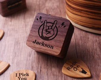 May include: A wooden music box with a rock and roll hand symbol and the name "Jackson" engraved on the lid. The box is surrounded by guitar picks with various sayings, including "Rock On" and "I Pick You Always".