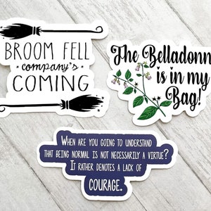May include: Three witch-themed stickers. The first sticker features a black broom with the text "BROOM FELL *company's* COMING". The second sticker features a green plant with purple flowers and the text "The Belladonna is in my Bag!". The third sticker is blue with white text that reads "WHEN ARE YOU GOING TO UNDERSTAND THAT BEING NORMAL IS NOT NECESSARILY A VIRTUE? IT RATHER DENOTES A LACK OF COURAGE."