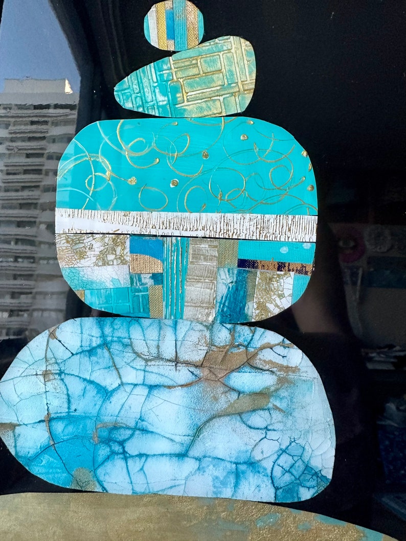Puede incluir: Una pila de cinco piedras abstractas, texturizadas, azules y doradas. Las piedras est&aacute;n apiladas una encima de la otra, con la piedra m&aacute;s grande en la parte inferior y la m&aacute;s peque&ntilde;a en la parte superior. Las piedras son de diferentes formas y tama&ntilde;os, y tienen una variedad de texturas, incluyendo lisas, rugosas y agrietadas.