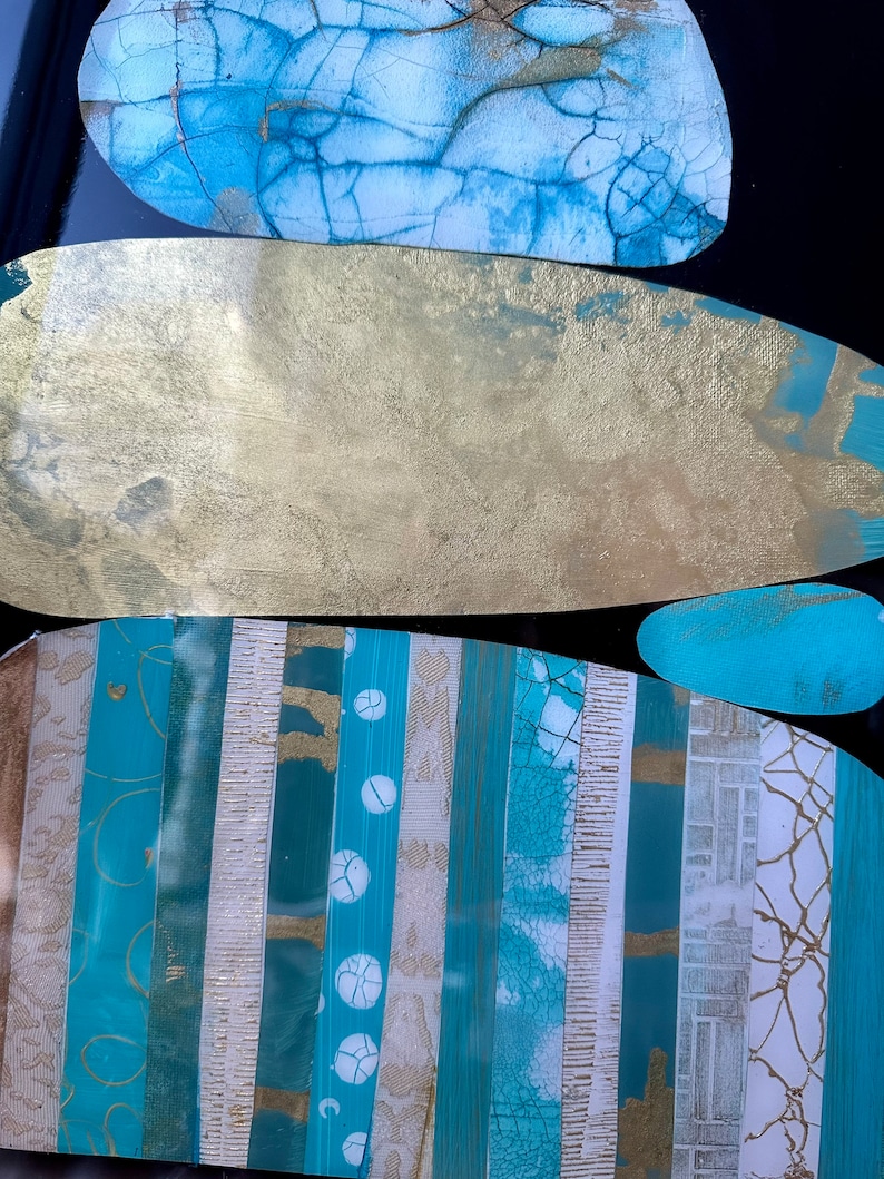 Puede incluir: Pintura abstracta con un dise&ntilde;o en capas. La pintura presenta un esquema de color azul, dorado y blanco con una variedad de texturas. La pintura est&aacute; sobre un fondo negro.