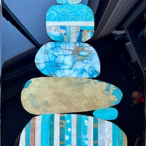 Puede incluir: Una pila de piedras azules y doradas con un dise&ntilde;o blanco y azul sobre un fondo negro.