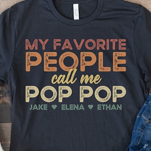 May include: A black t-shirt with the text "My Favorite People call me Pop Pop" in a vintage style font. The names Jake, Elena, and Ethan are listed below the text with heart symbols between each name.