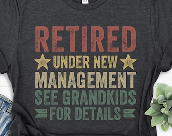May include: A dark grey t-shirt with a vintage-style graphic that reads "Retired Under New Management See Grandkids For Details".