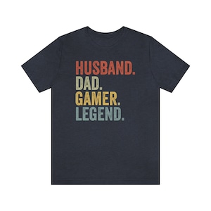 May include: A navy blue t-shirt with the text "Husband. Dad. Gamer. Legend." in a vintage style font with colorful accents.