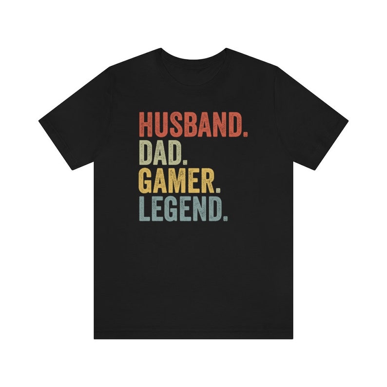May include: Black t-shirt with a vintage-style graphic that reads "Husband. Dad. Gamer. Legend."