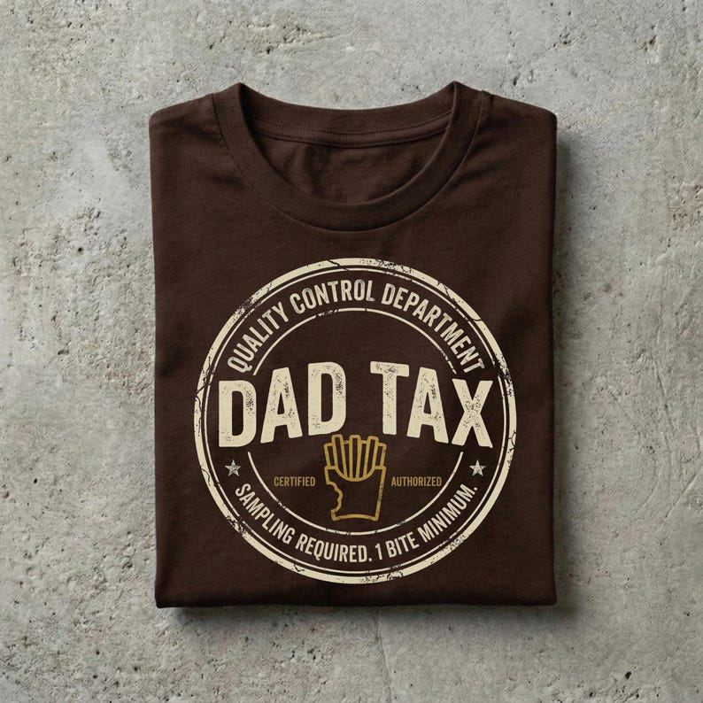 Puede incluir: Una camiseta marr&oacute;n doblada con un gr&aacute;fico circular que dice "Quality Control Department DAD TAX Certified Sampling Required. 1 Bite Minimum." El gr&aacute;fico incluye un dibujo de patatas fritas.