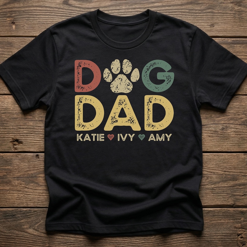 A personalized retro vintage 'Dog Dad' t-shirt featuring custom dog names printed in distressed typography. A perfect custom Father's Day or birthday gift from the dog.