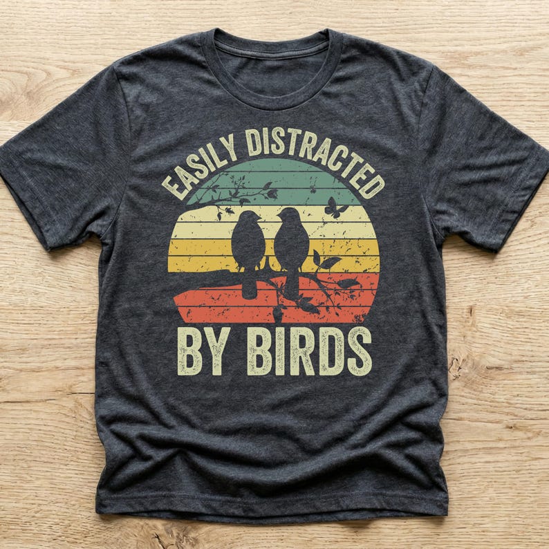 A retro vintage sunset t-shirt reading Easily Distracted By Birds. A funny bird watching shirt and great gift for bird lovers and birding enthusiasts.