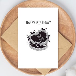 Pode incluir: Um cartão branco com o texto "Happy Birthday" e uma ilustração em preto e branco de um bolo com o texto "RIP 20's" no topo.