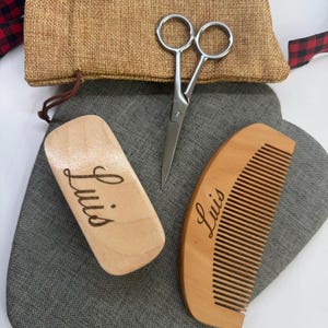 May include: A grooming kit with a wooden comb and case, both engraved with the name "Luis", a pair of silver scissors, and a burlap bag. The text "Option 1 font" is above the scissors.