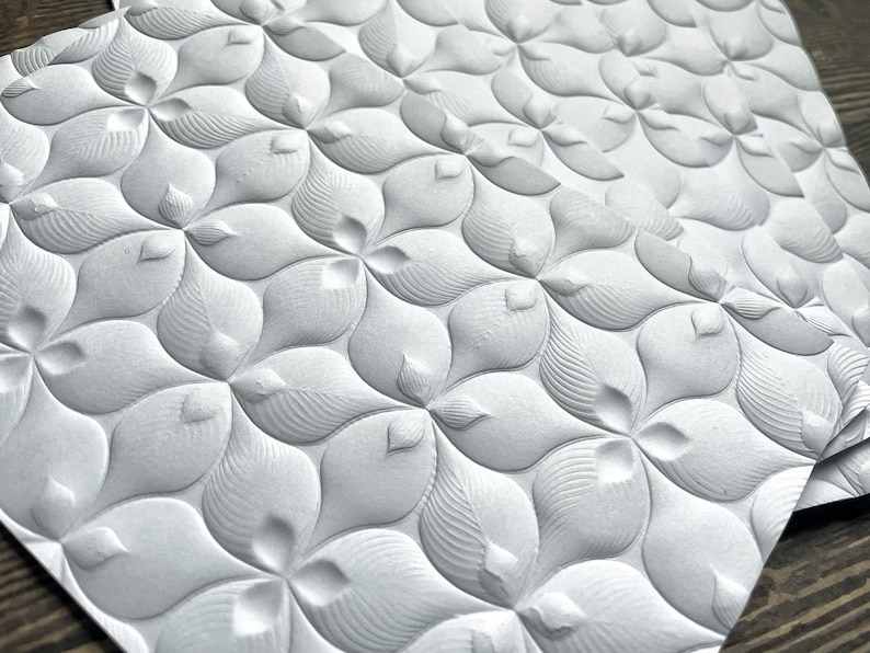May include: A white textured paper with a repeating pattern of embossed flower shapes.