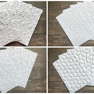 May include: Five white embossed paper sheets with different patterns. The patterns include a floral design, a vine design, and a geometric design.
