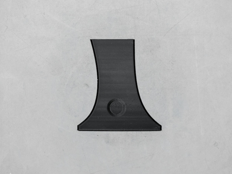 May include: A black plastic base with a rounded opening in the center. The base is designed to hold a small object, such as a candle or a vase.