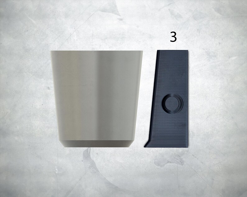 May include: A gray ceramic cup and a black plastic cup holder with a round hole in the center. The cup holder has the number "3" printed on it.