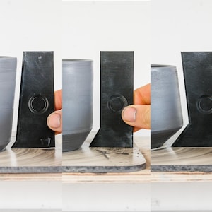 Puede incluir: Cuatro tazas de cerámica grises con anillos de plástico negro alrededor de la parte superior. Los anillos tienen un recorte circular en el centro.