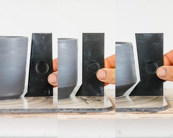 May include: Four grey ceramic cups with black plastic rings around the top. The rings have a circular cutout in the centre.