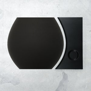 Könnte beinhalten: Eine schwarze und silberne Spielekonsole mit einem runden Knopf auf der rechten Seite.