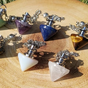 May include: Seven different coloured crystal pendulums with silver chains. The crystals are green, purple, blue, black, white, and clear.