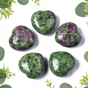 May include: Five polished heart-shaped stones made of green zoisite with embedded magenta ruby inclusions and black mineral flecks. Each stone features a smooth, glossy surface with a distinct mottled pattern of vibrant pink and deep forest green.