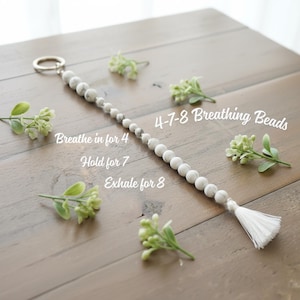 May include: White and grey beaded keychain with a silver ring and a white tassel. The text on the image reads "4-7-8 Breathing Beads" and instructions: "Breathe in for 4, Hold for 7, Exhale for 8."