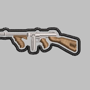 May include: A black and white embroidered patch of a silver-colored machine gun with brown wooden grips.