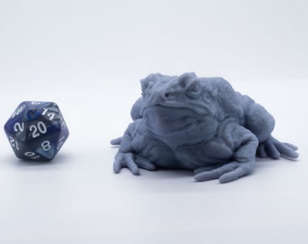 May include: A blue and grey 20-sided die next to a grey 3D printed toad figurine.
