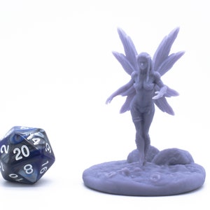 Könnte beinhalten: Eine violette Plastik-Miniaturfigur einer Fee mit ausgebreiteten Flügeln. Die Fee steht auf einem runden Sockel mit einer strukturierten Oberfläche. Ein blauer und schwarzer 20-seitiger Würfel befindet sich im Vordergrund.