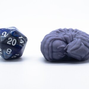 May include: A blue and black 20-sided die with white numbers and a purple 3D printed creature.