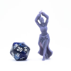 Puede incluir: Una miniatura impresa en 3D de color púrpura de una mujer en una pose de baile. Lleva una falda larga y una blusa con un cinturón decorativo. Un dado de 20 caras azul y negro está en primer plano.