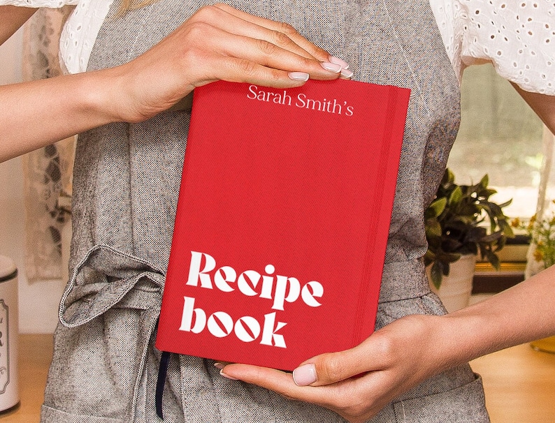 Puede incluir: Un libro de recetas de tapa dura rojo con el texto "Sarah Smith's Recipe Book" en letras blancas.