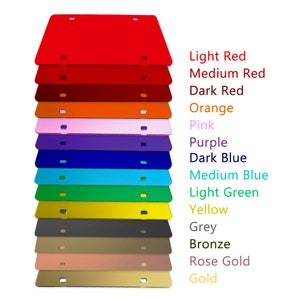 May include: A stack of 15 blank license plates in various colors, including light red, medium red, dark red, orange, pink, purple, dark blue, medium blue, light green, yellow, grey, bronze, rose gold, and gold.