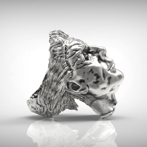 May include: A silver ring with a detailed sculpture of a person's head. The head is tilted back and the person's eyes are closed.