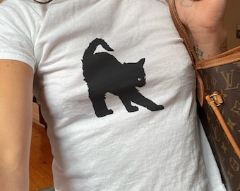 May include: A white t-shirt with a black silhouette of a cat on the front.