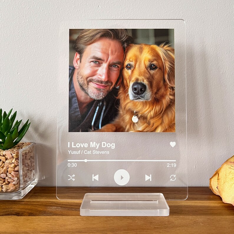 May include: Clear acrylic photo display featuring a man and a golden retriever. The image is printed with the text "I Love My Dog" and a music player interface. The display is supported by a clear acrylic base.