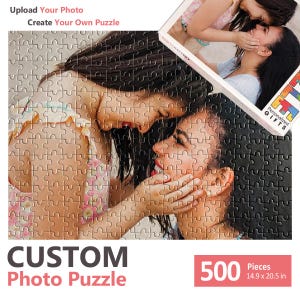 May include: A 500-piece custom photo puzzle measuring 37.8 by 52.1 cm. The puzzle features a printed image of two people embracing, with text reading Upload Your Photo Create Your Own Puzzle, Personalized GIFTS, and 500 Pieces 14.9 x 20.5 in.