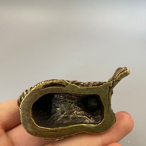 May include: A small, antique-style brass figurine. The figurine has a detailed, textured surface with a dark patina. The object appears to be a religious or decorative item, possibly a small statue or sculpture.