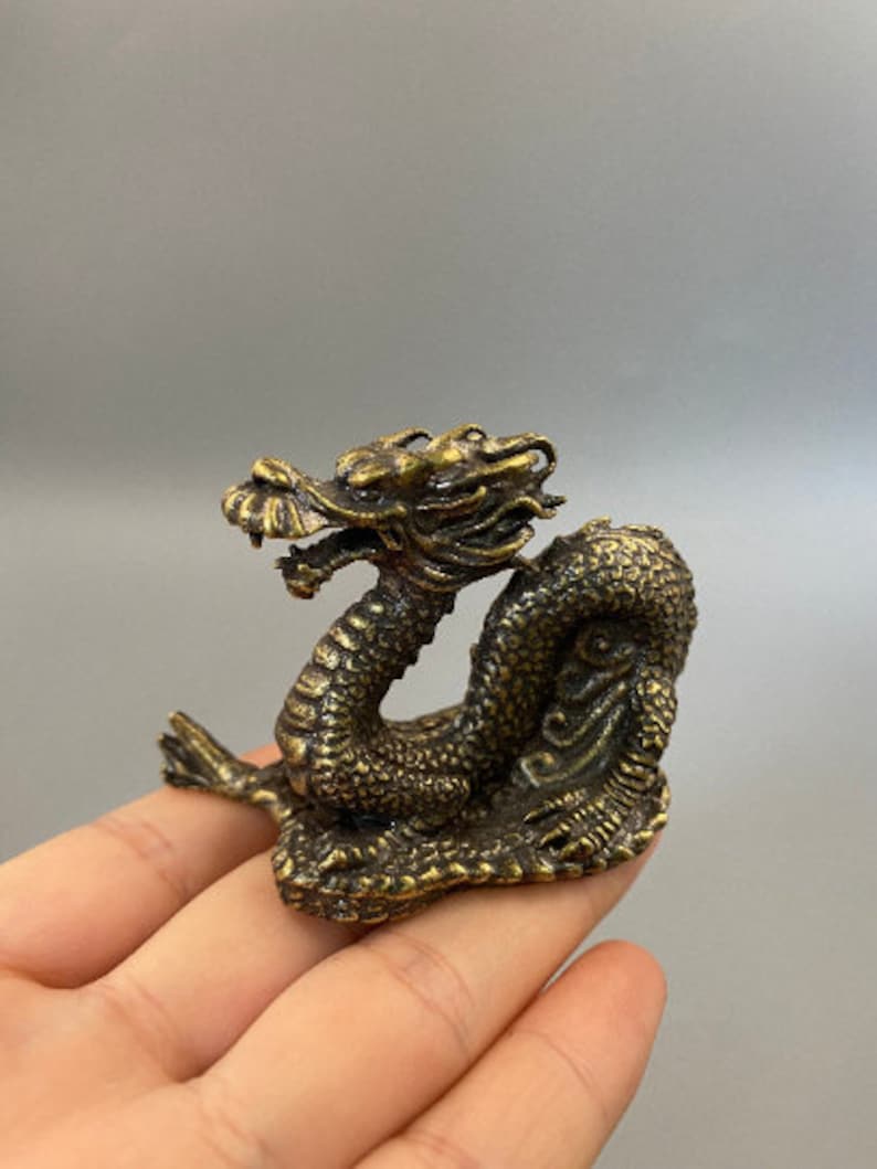 May include: A detailed bronze dragon figurine with intricate scales and a detailed head. The dragon is posed in a coiled position, with its head raised. The figurine is a decorative item, likely for display or collection.